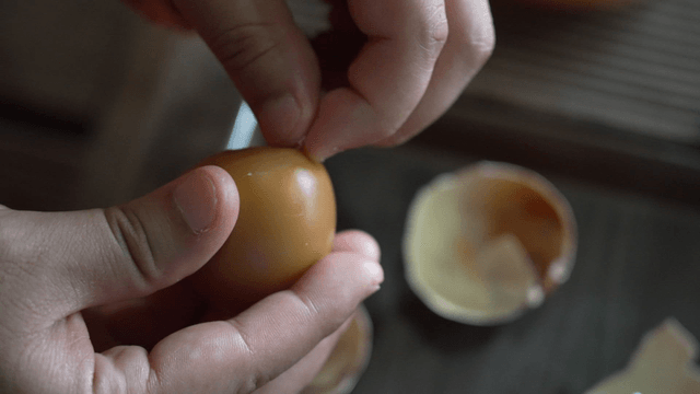 Hands peeling roasted egg shell