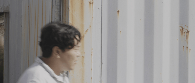 Man coming out between containers and looking at a couple