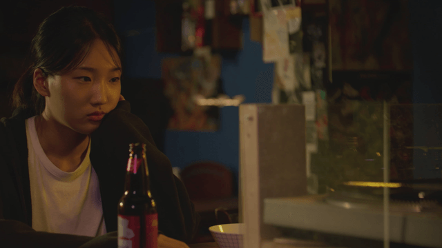 Woman lost in thought with a beer bottle in a record bar