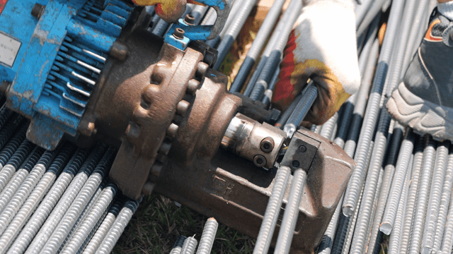 Worker cutting steel bars with a machine