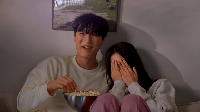 Couple watching scary movie with popcorn on sofa