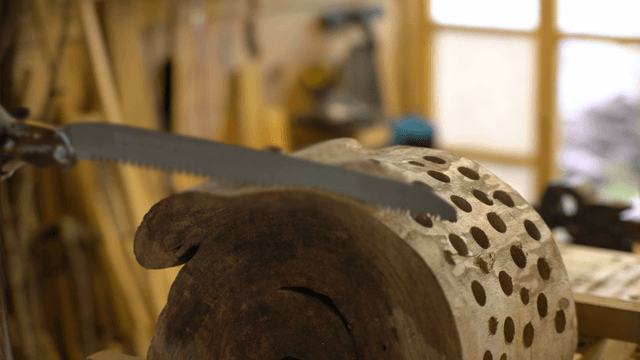 Carpenter starting to saw a wooden board with many holes