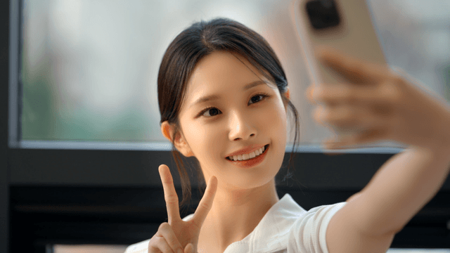 Young woman taking a selfie by the window