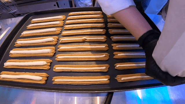 Person piping churro dough onto an oven tray
