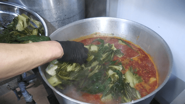 Outer leaves added into red broth in a large pot