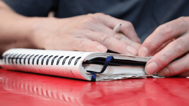 Person flipping through a notebook on a table