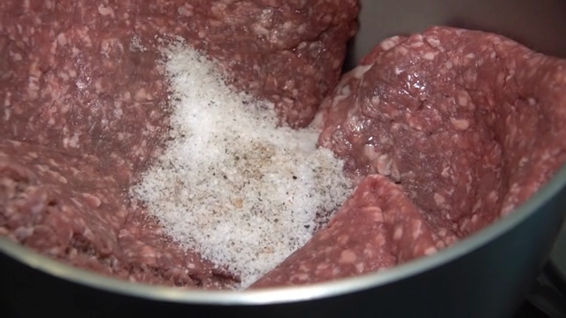 Salt and pepper on minced meat in a bowl