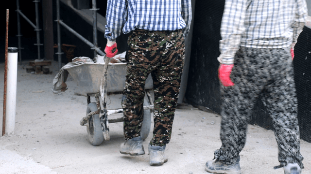 Workers pushing a wheelbarrow at a site