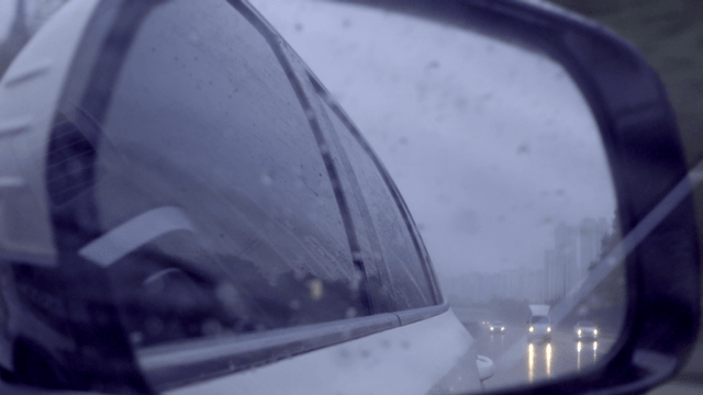 Rainy road seen through side mirror of moving car