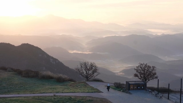 A person walking on a mountain path at sunrise