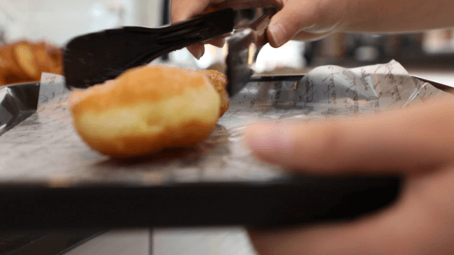 Placing a donut on a tray with tongs