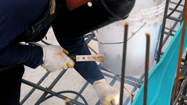 Worker welding metal rods at a construction site
