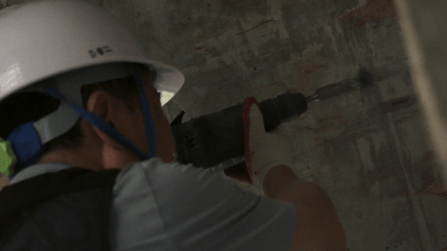 Worker drilling into a concrete wall
