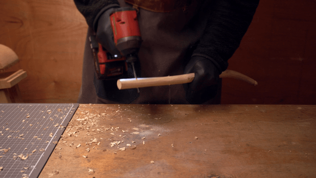Person drilling a wooden stick in a workshop