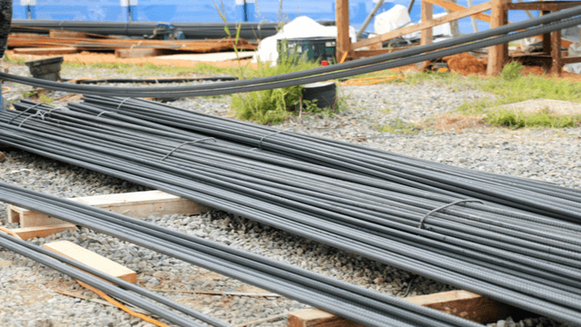 Workers handling steel rods at a construction site