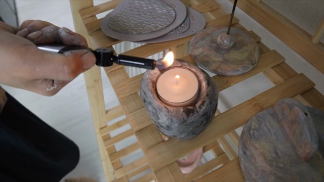 Lighting a candle on a wooden shelf