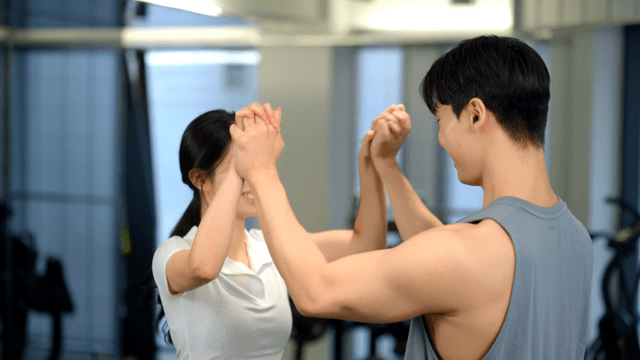 Couple encouraging each other while holding hands at gym
