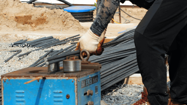 Worker bending steel bars at a construction site