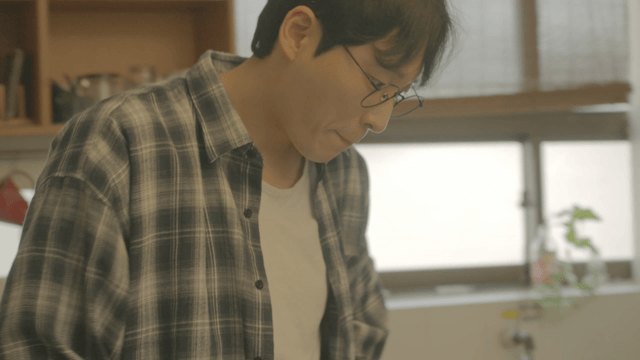 Man with glasses wearing check shirt at home