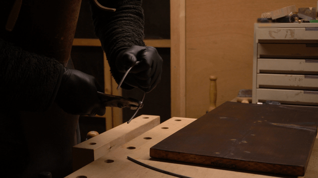 Metal artisan bending wire with tools in workshop