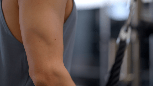 Man training arms with rope in gym