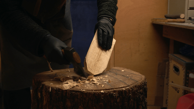 Artisan carving wood with an axe in workshop