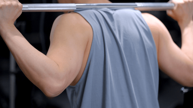 Man performing squat with weighted bar on shoulders