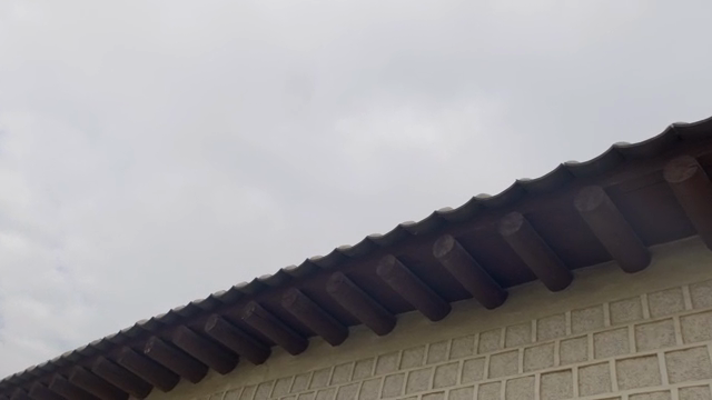 Traditional Korean house roof under cloudy sky