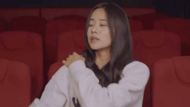 Woman sitting alone in a theater stands up