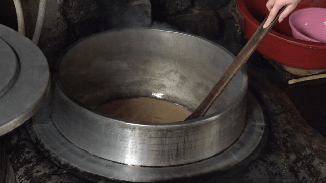 Wooden spatula stirring ground acorn liquid in a pot