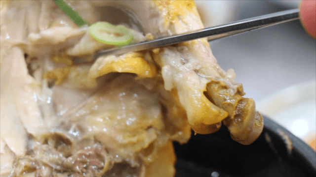 Chopsticks lifting a chicken leg from phellinus linteus ginseng chicken soup