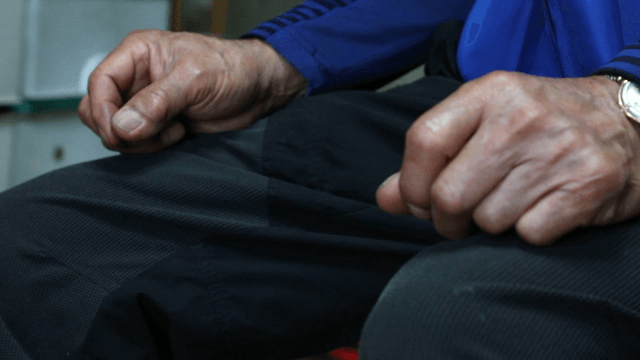 Elderly hands resting on knees indoors