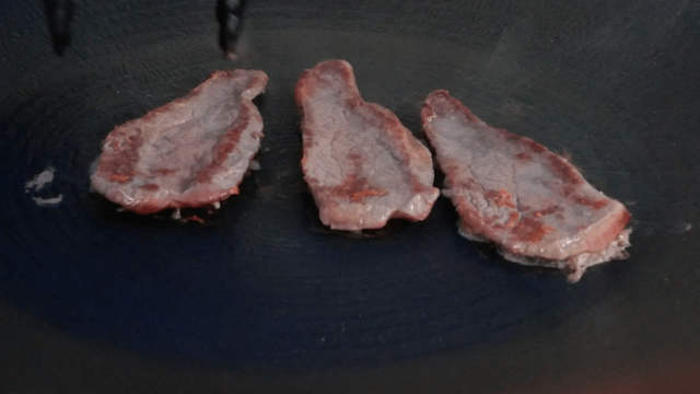 Sizzling meat slices on a hot pan