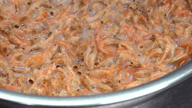 Dried shrimp in stainless bowl with soybean broth on kitchen counter