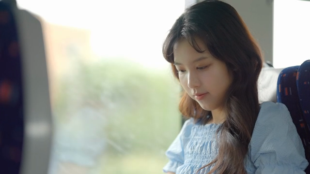 이어폰을 끼는 기차 안의 젊은 여성