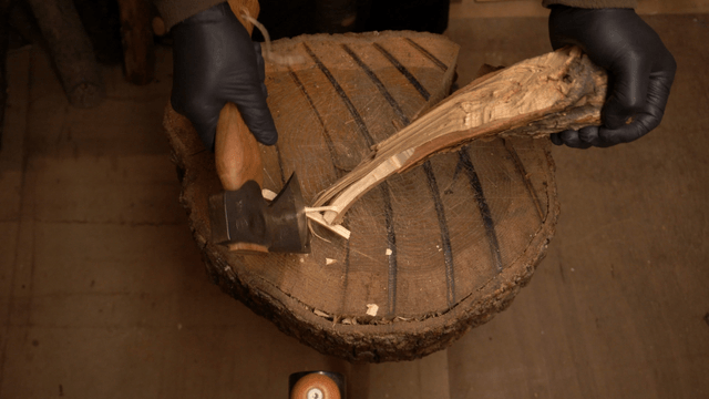 Woodcraft artisan trimming a wooden block with an axe