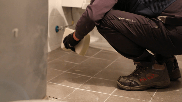 Worker cleaning tiles in a bathroom
