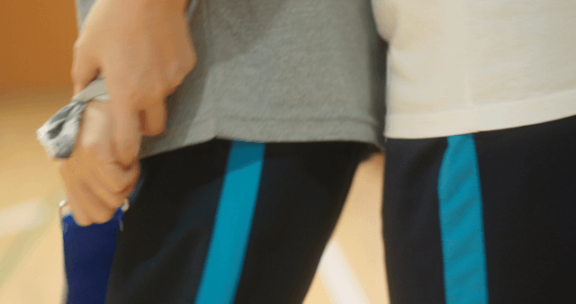 Two people holding a blue ribbon indoors