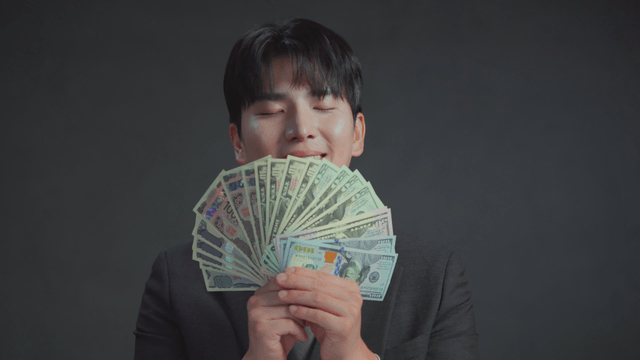 Man smelling money with a satisfied expression