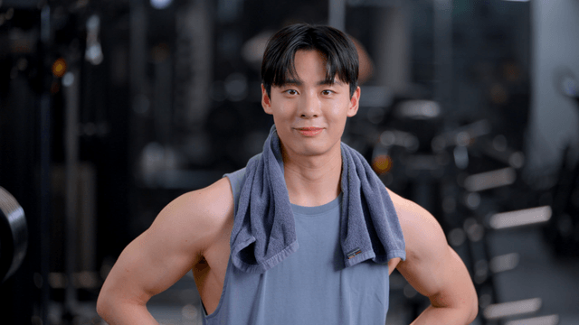 Young man facing forward with a towel around his neck at gym