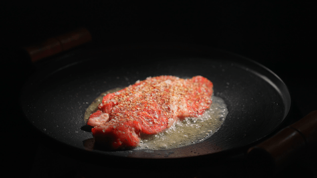 Steak sizzling in a hot pan