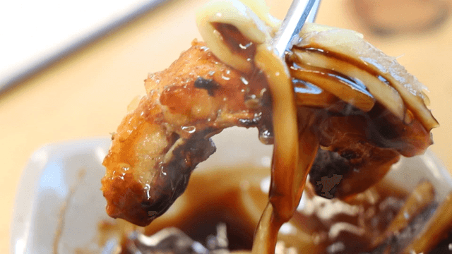 Chopsticks picking up grilled eel with ginger soy sauce