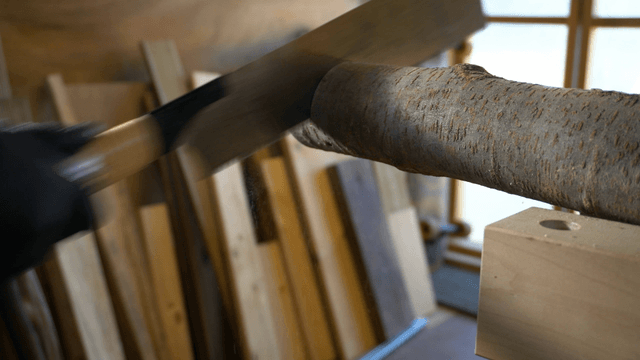 Hands sawing a wooden log with a saw