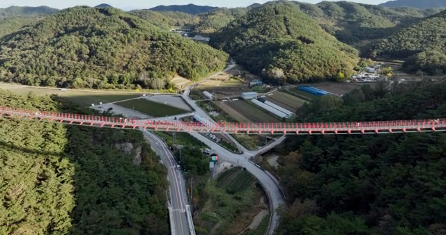 Red swing bridge on green hill
