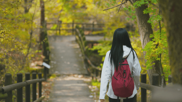 Young woman with long hair walking down autumn forest path
