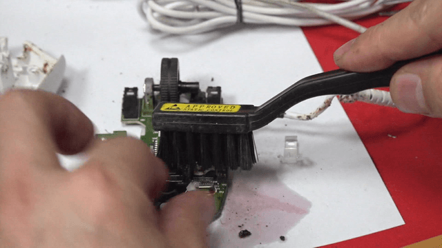 Brush cleaning a mouse circuit board
