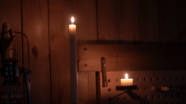 Flickering candles fading in a dark wooden room