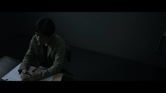 Man sitting at table with documents in dark room