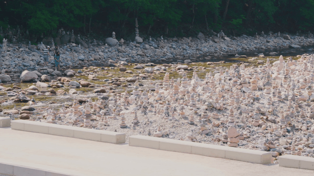 People resting by riverside with many stone towers