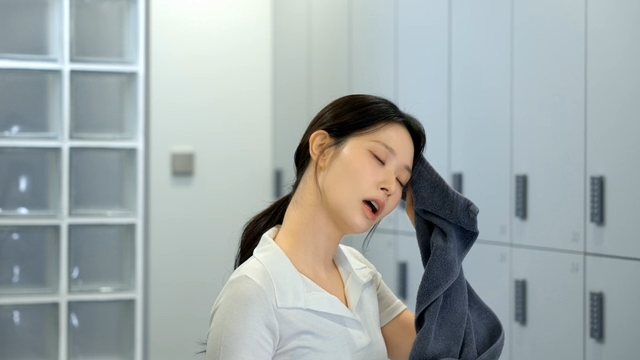 Young woman wiping sweat with a towel in a locker room